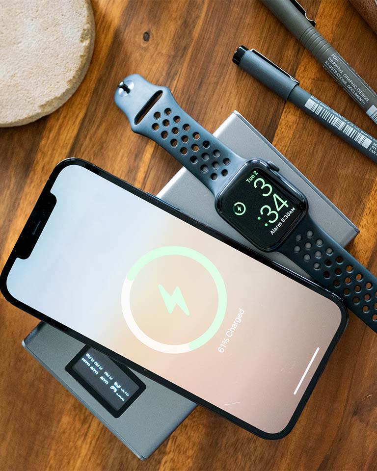 Image of Graphene Powerbank, Flash Pro Plus, with 25000mAh large battery capacity, OLED display, USB-C 100W fast charging. An iPhone 14 is being charged on the MagSafe compatible wireless charging up to 15W. An Apple Watch is being charged on the separate Apple Watch charging pad supporting up to 5W. Perfect for Apple users on the go. 
